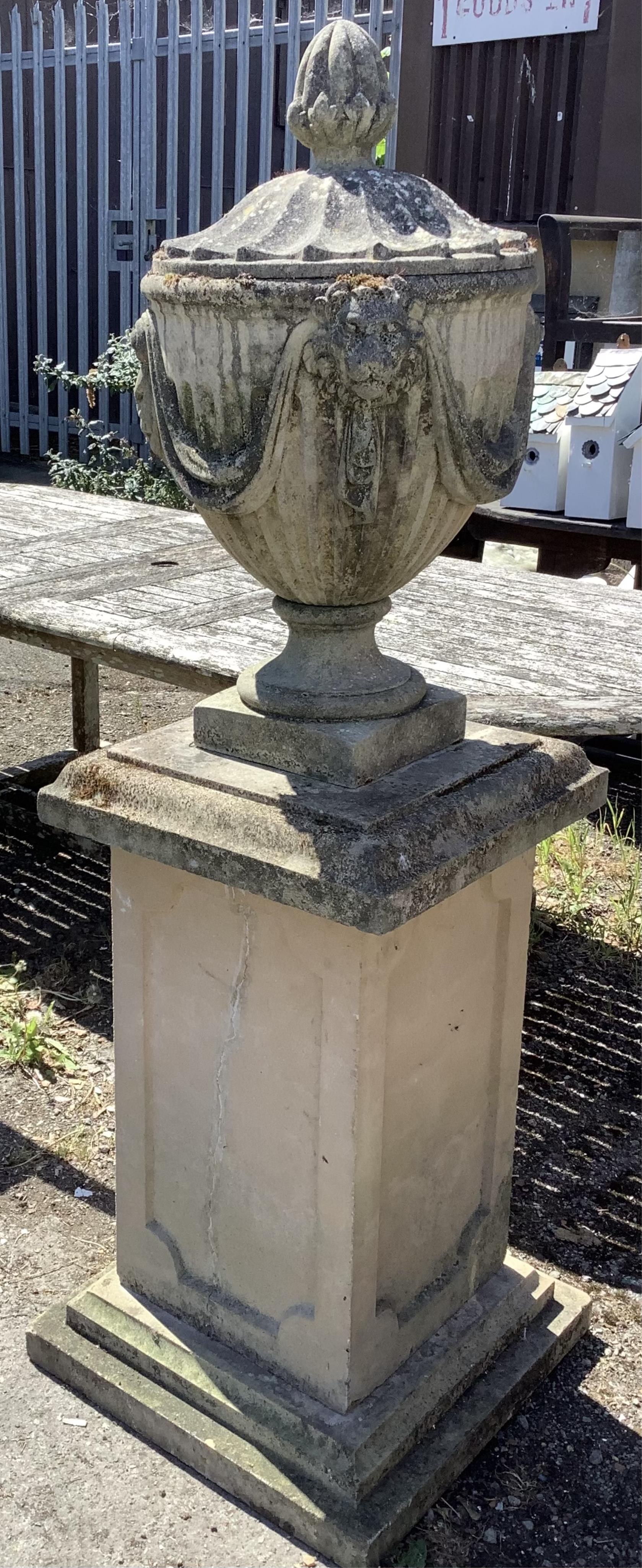 A reconstituted stone Adam style lidded garden urn on a square pedestal base, height 160cm